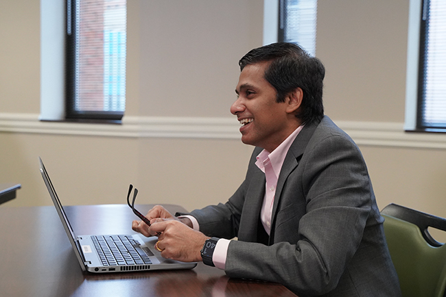 Businessman with laptop at a desk smiles during a conversation