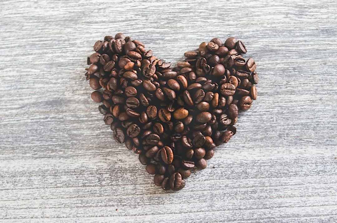 coffee grounds in the shape of a heart on a gray wooden table