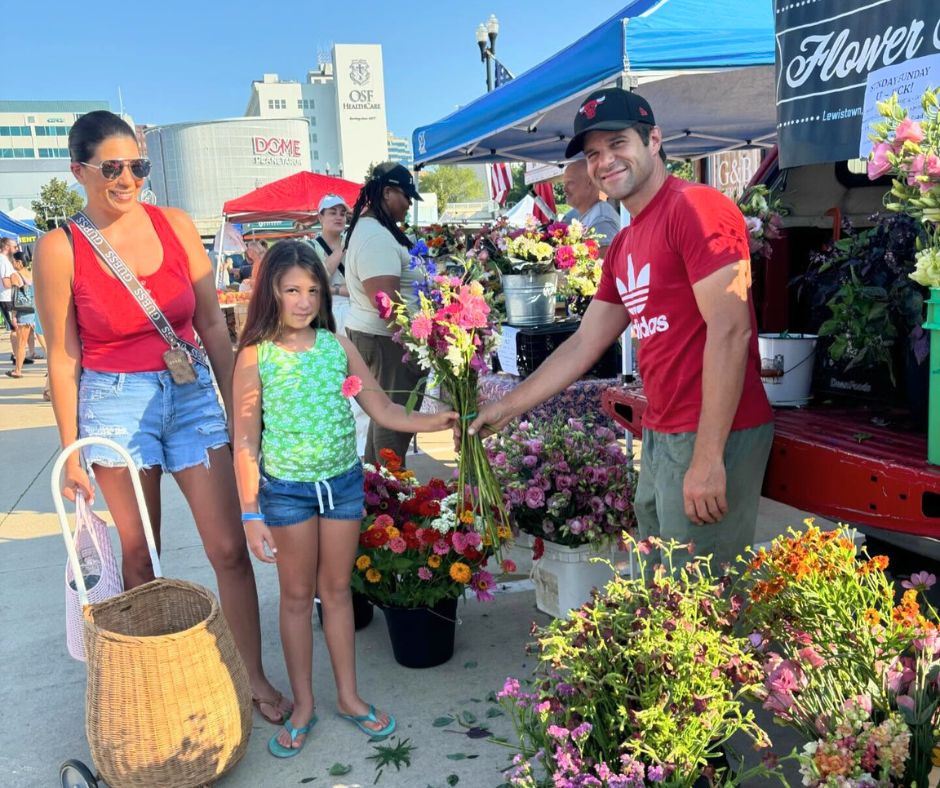 a group of people posing with a bouquet of flowers at the Farmers Market