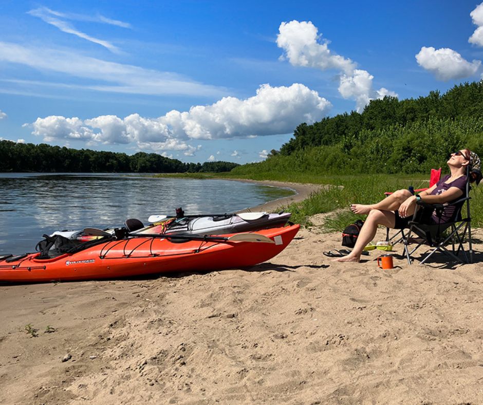 person relaxing on a beach with a kayak on the shore