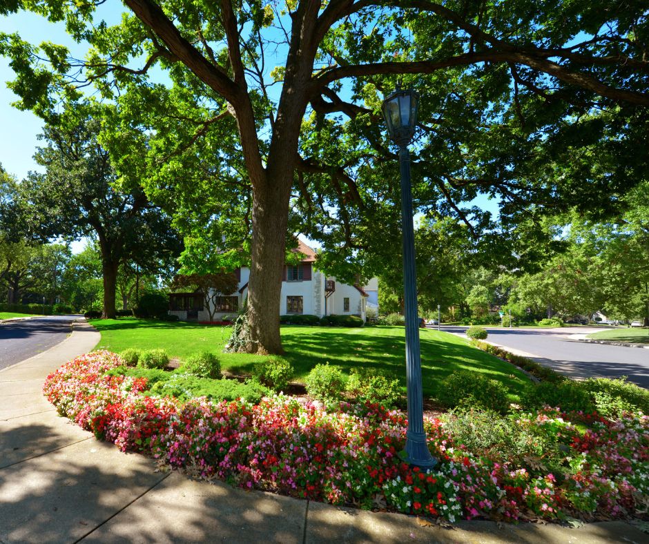 trees, flowers and a lightpost in front of a residence